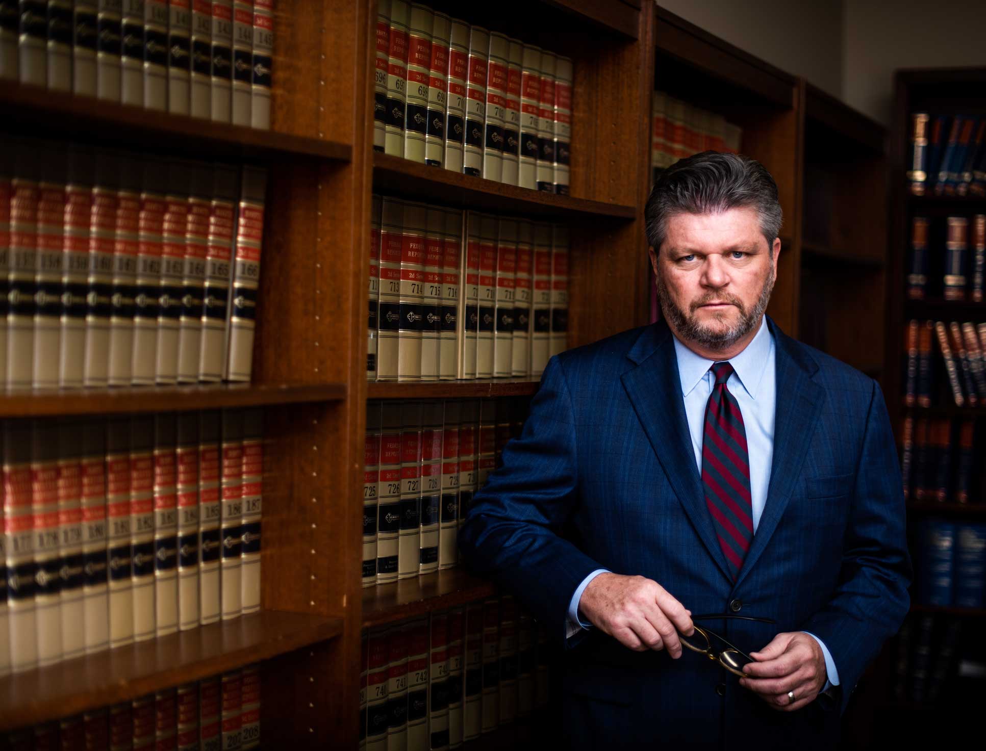 John Harralson leaning against a full bookcase of law books